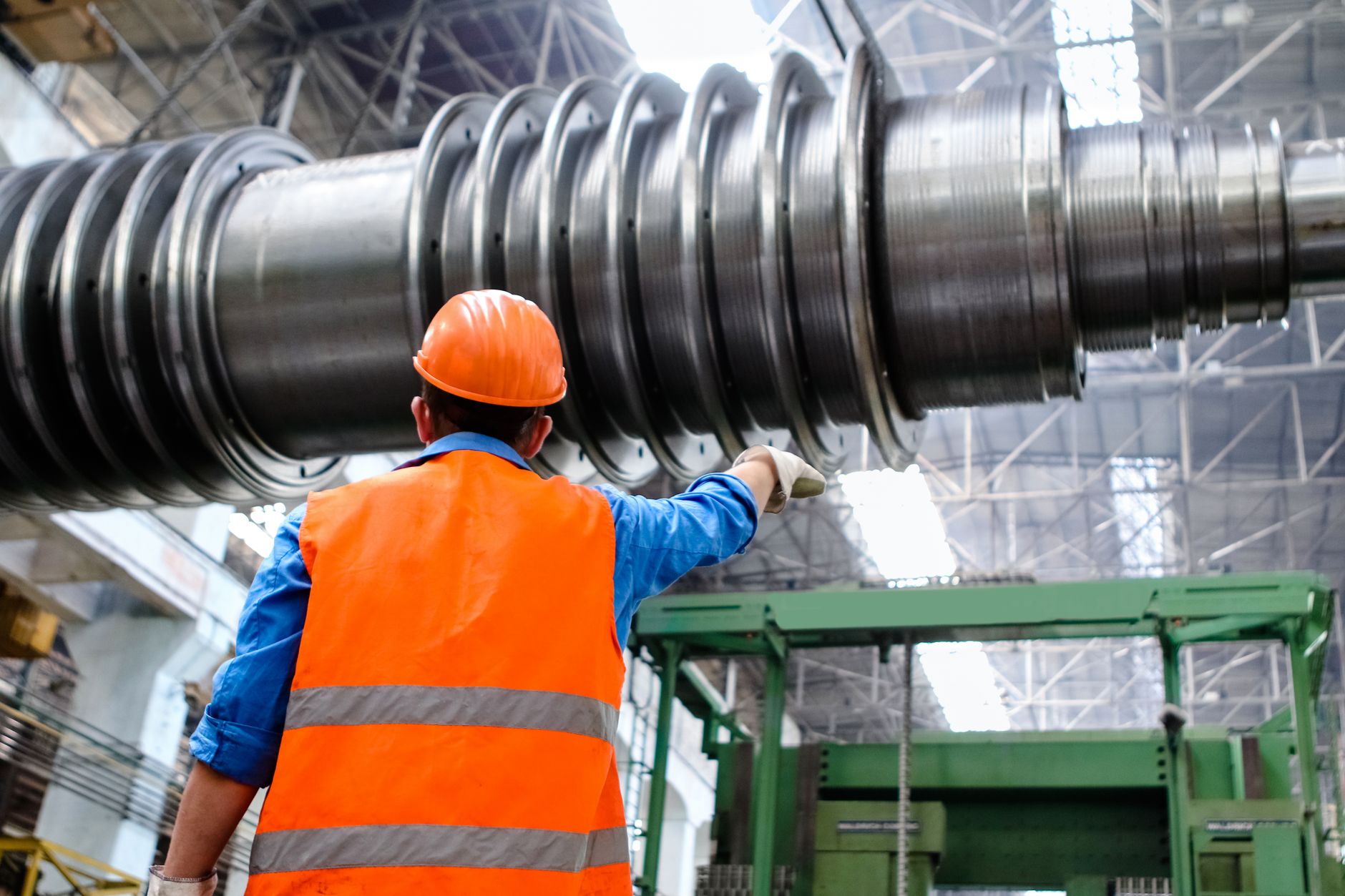 Engineer in a hard hat and high-visibility vest inspecting large machinery