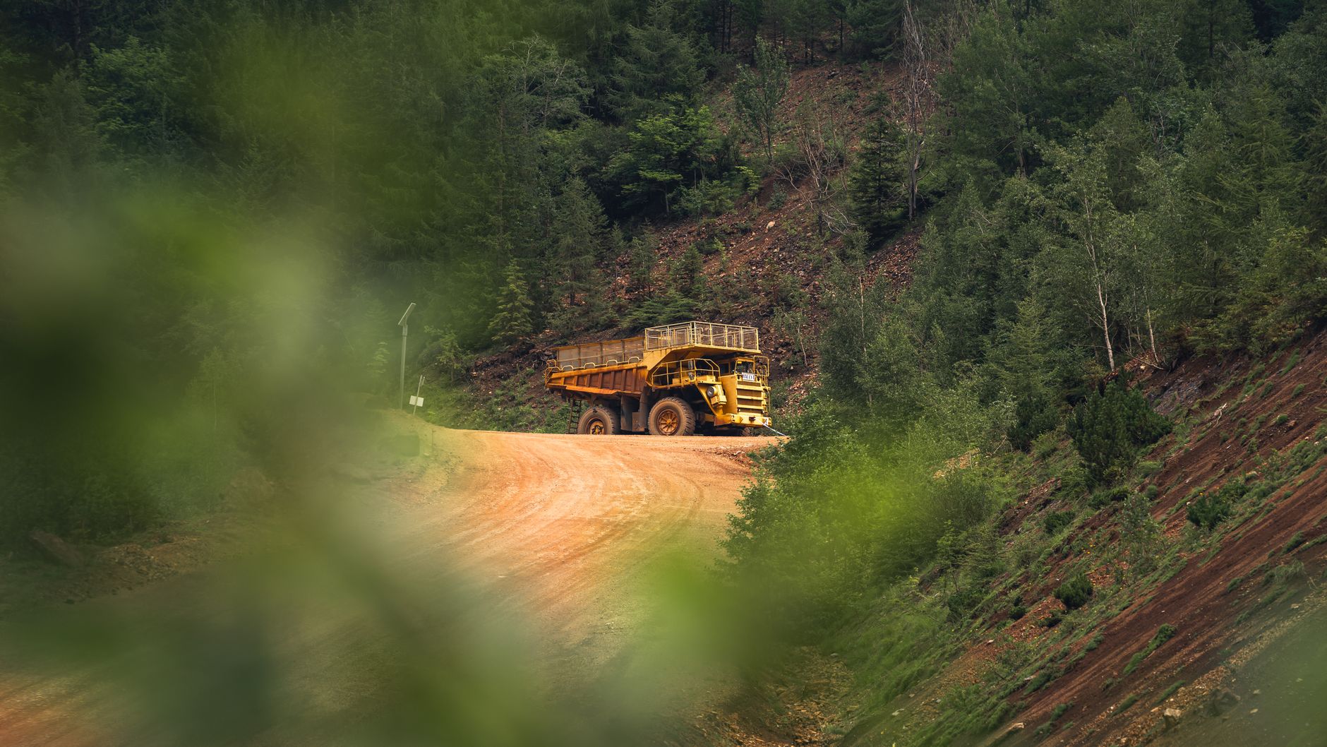 Mining haul truck on a road through dense northern forest